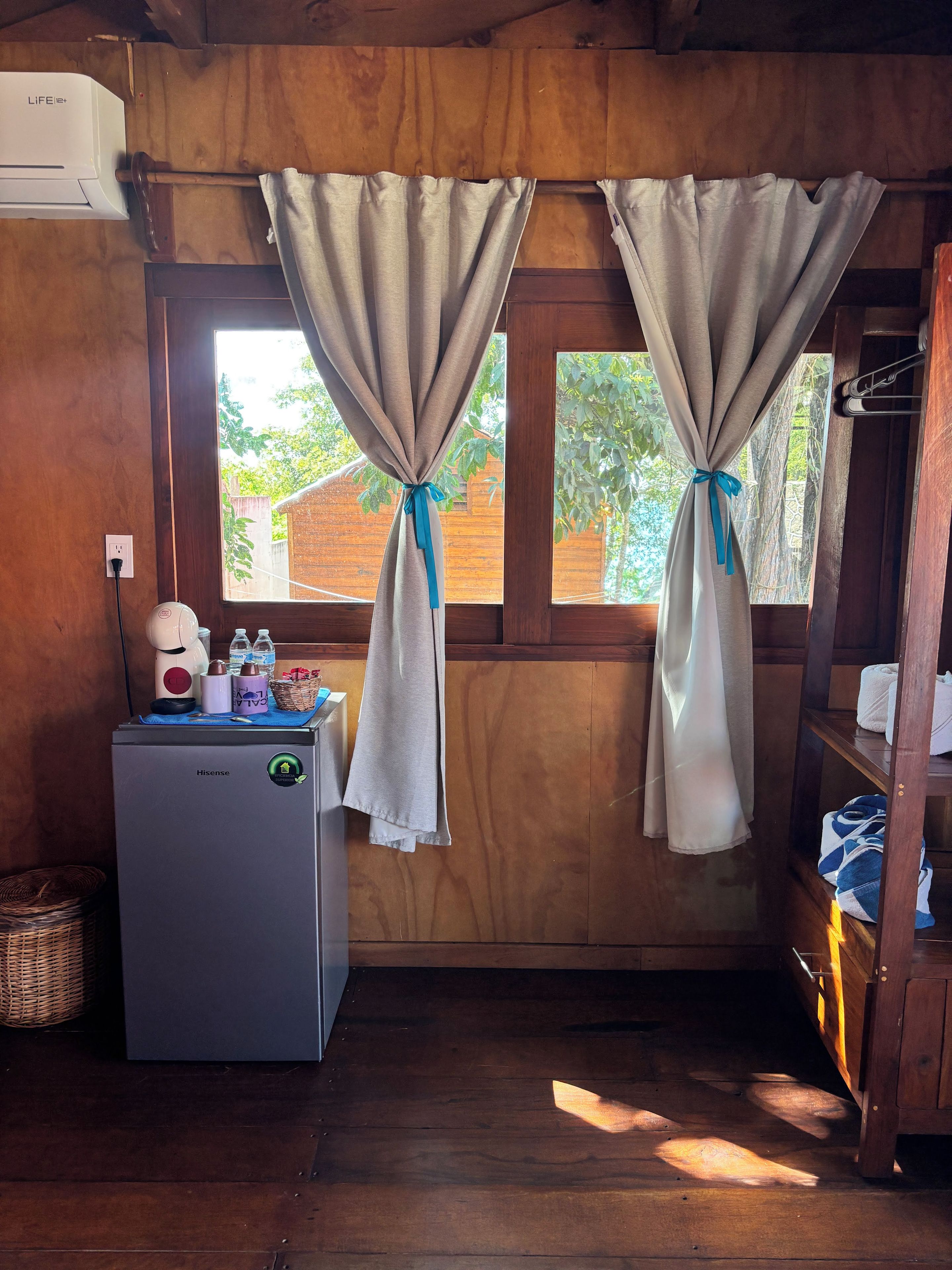 Ein gemütlicher Raum mit kleinem Kühlschrank, Wasserspender und Ablagefläche für Handtücher und Schuhe.