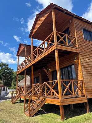 Ein Holzhaus mit Balkon, Treppe und einem Strohdach.