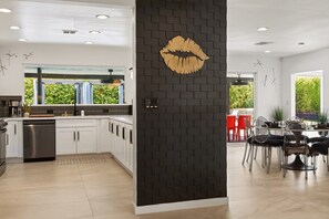 Une cuisine moderne avec des meubles blancs, un mur d’accent en briques noires et une grande fenêtre.