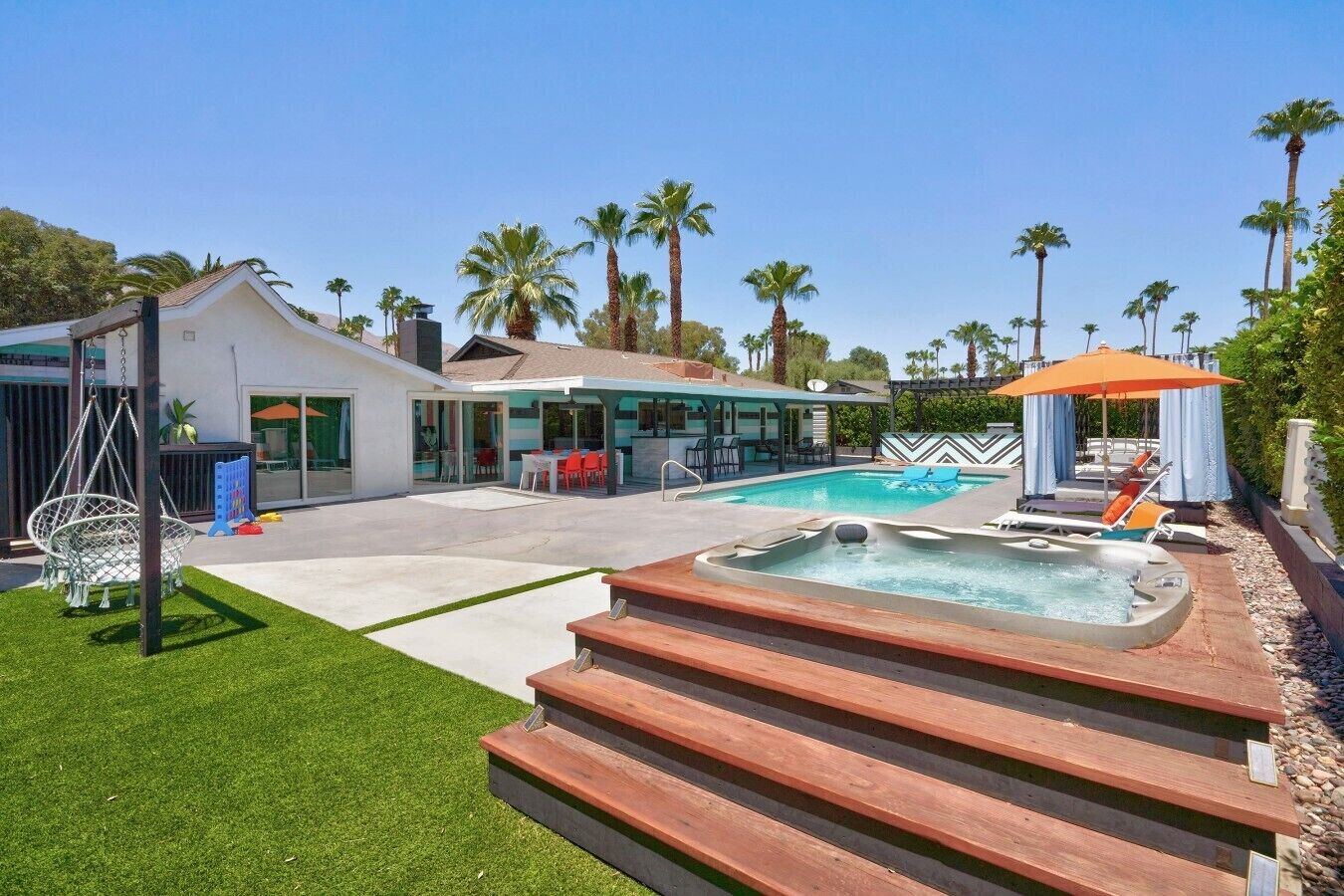 A modern house with a swimming pool, a hot tub, and a patio area.