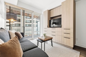 Una sala de estar moderna con un sofá, una mesa de centro y un televisor montado en un mueble de madera.