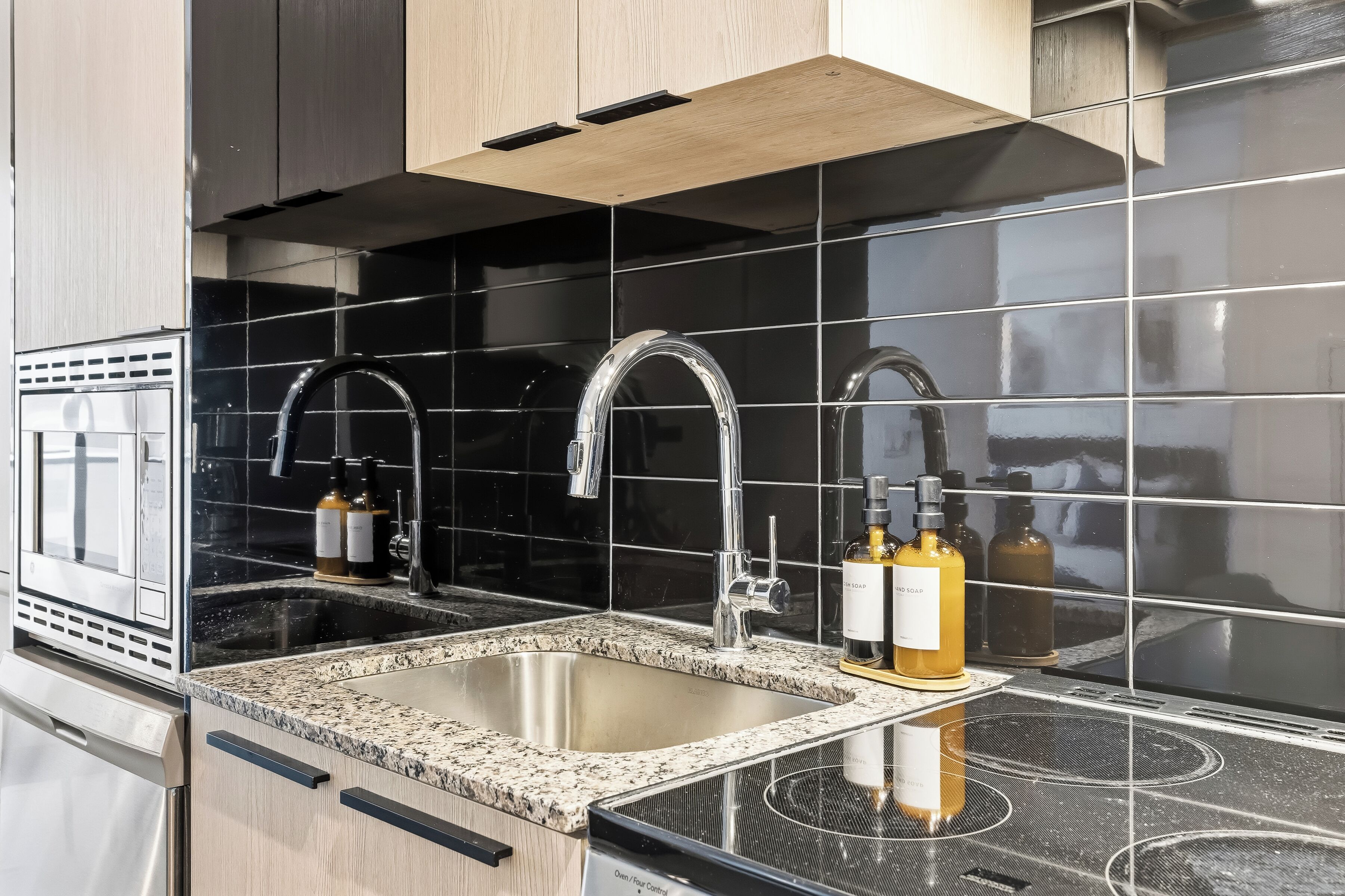 Een moderne keuken met een roestvrijstalen spoelbak, twee kranen en een granieten aanrecht.