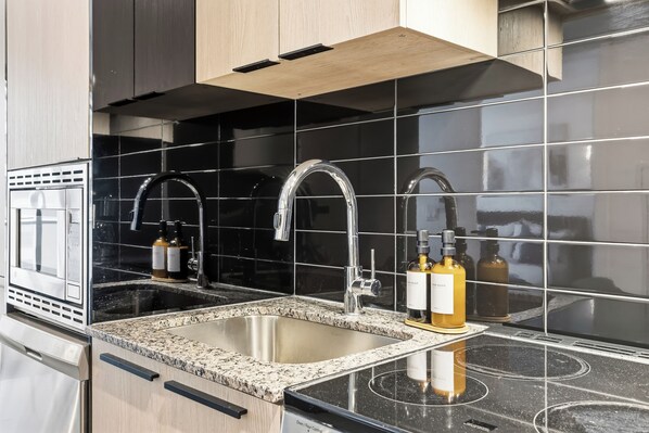 Una cocina moderna con un lavamanos de acero inoxidable, dos grifos y una encimera de granito.