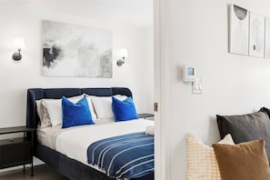 Ein modernes Hotelzimmer mit Bett, Nachttischen, einer Wandleuchte und Kunstwerken.
