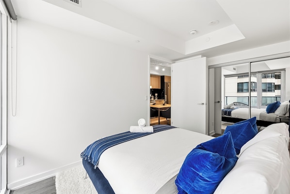 Habitación de hotel moderna con una cama grande, una zona de estar independiente y vistas a la ciudad a través de la ventana.