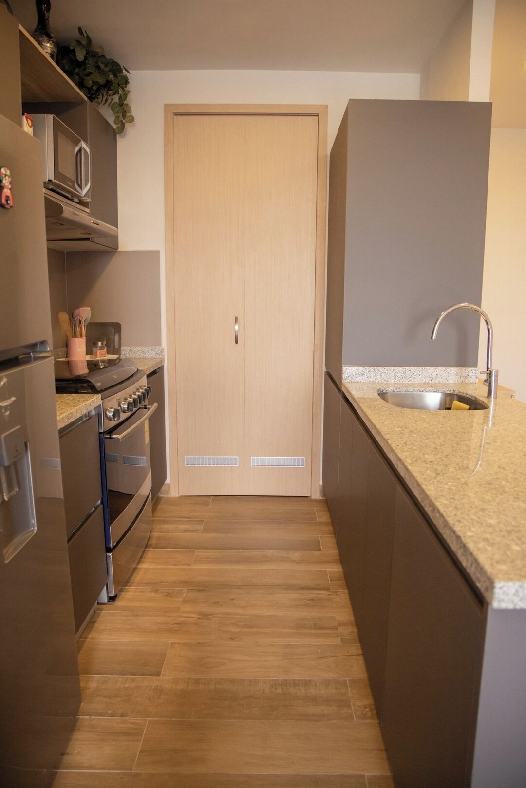 Eine Küche mit Holztür, Edelstahlgeräten und einer Arbeitsplatte aus Granit.