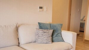 Un salon avec un canapé, une table basse ronde et une télécommande posée sur la table.