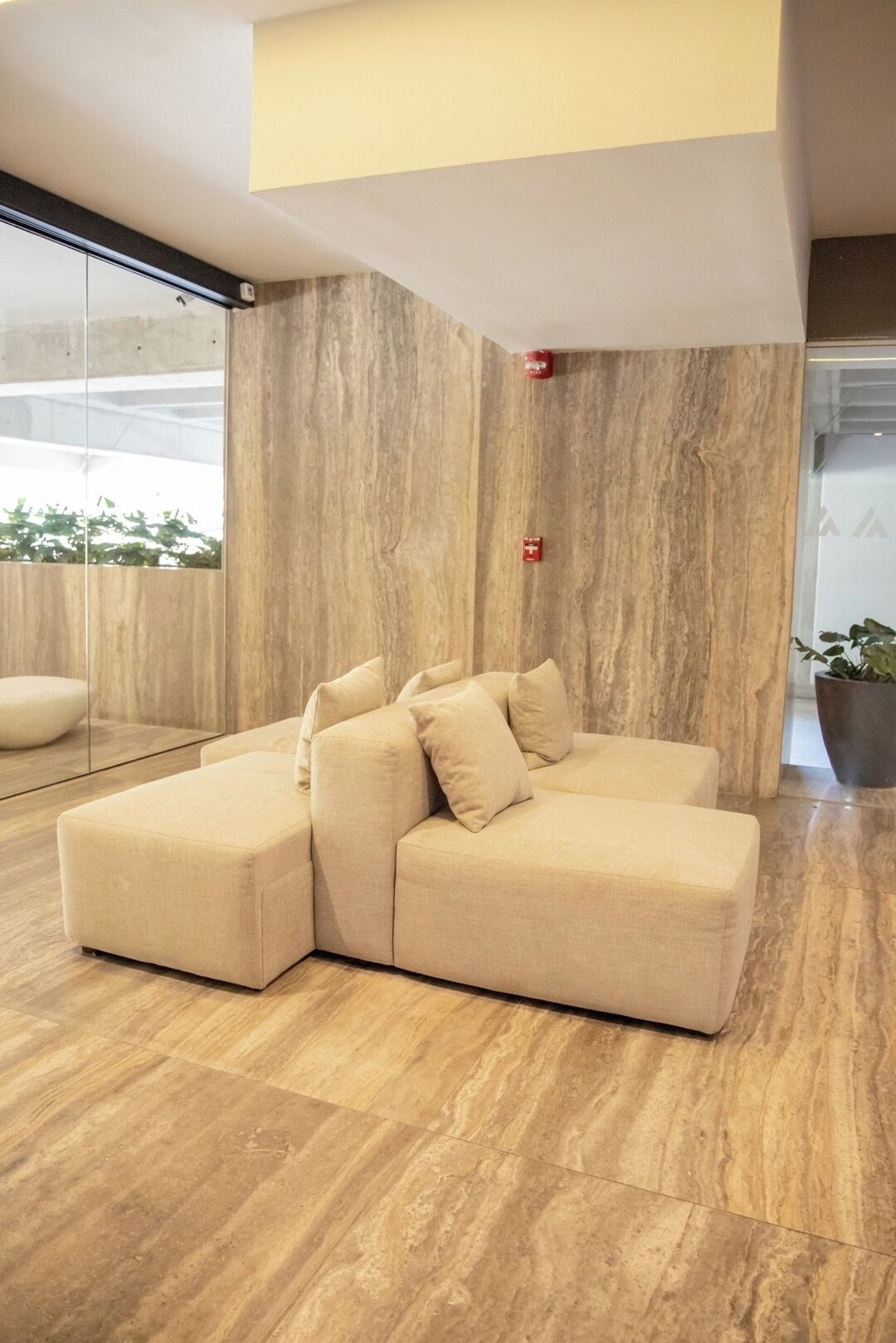 Ein modernes Wohnzimmer mit einem Ecksofa, einer Glastrennwand und Holzboden.
