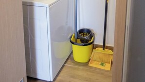 Une buanderie équipée d’un lave-linge, d’une serpillière et d’un balai.