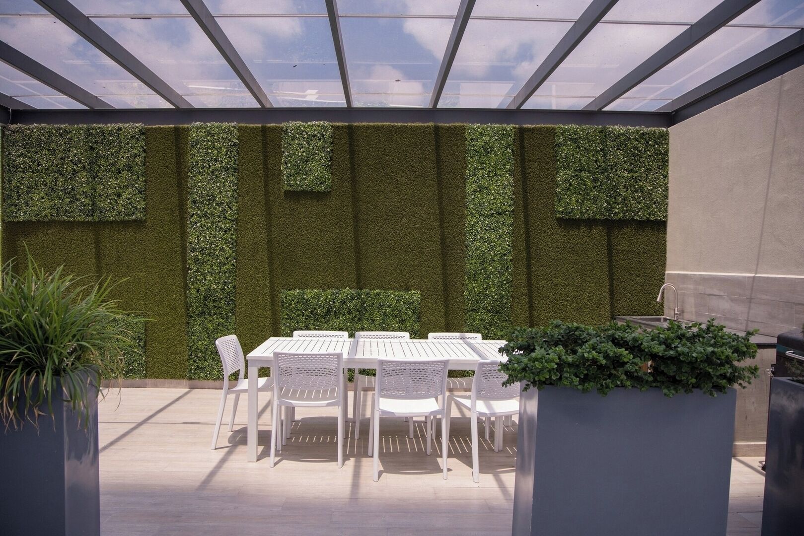Eine Außenpatio mit Tisch und Stühlen, umgeben von vertikalen Grünflächen.