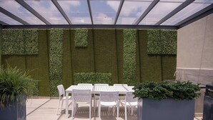Une terrasse extérieure avec une table et des chaises, entourée de jardins verticaux.
