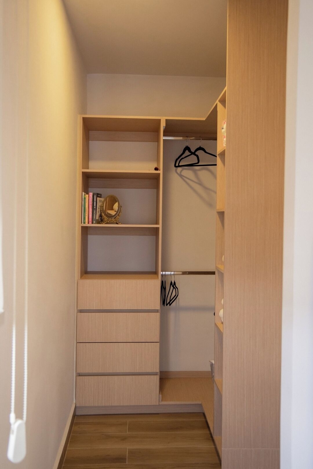 A walk-in closet with wooden shelving, a hanging rod, and a small mirror.