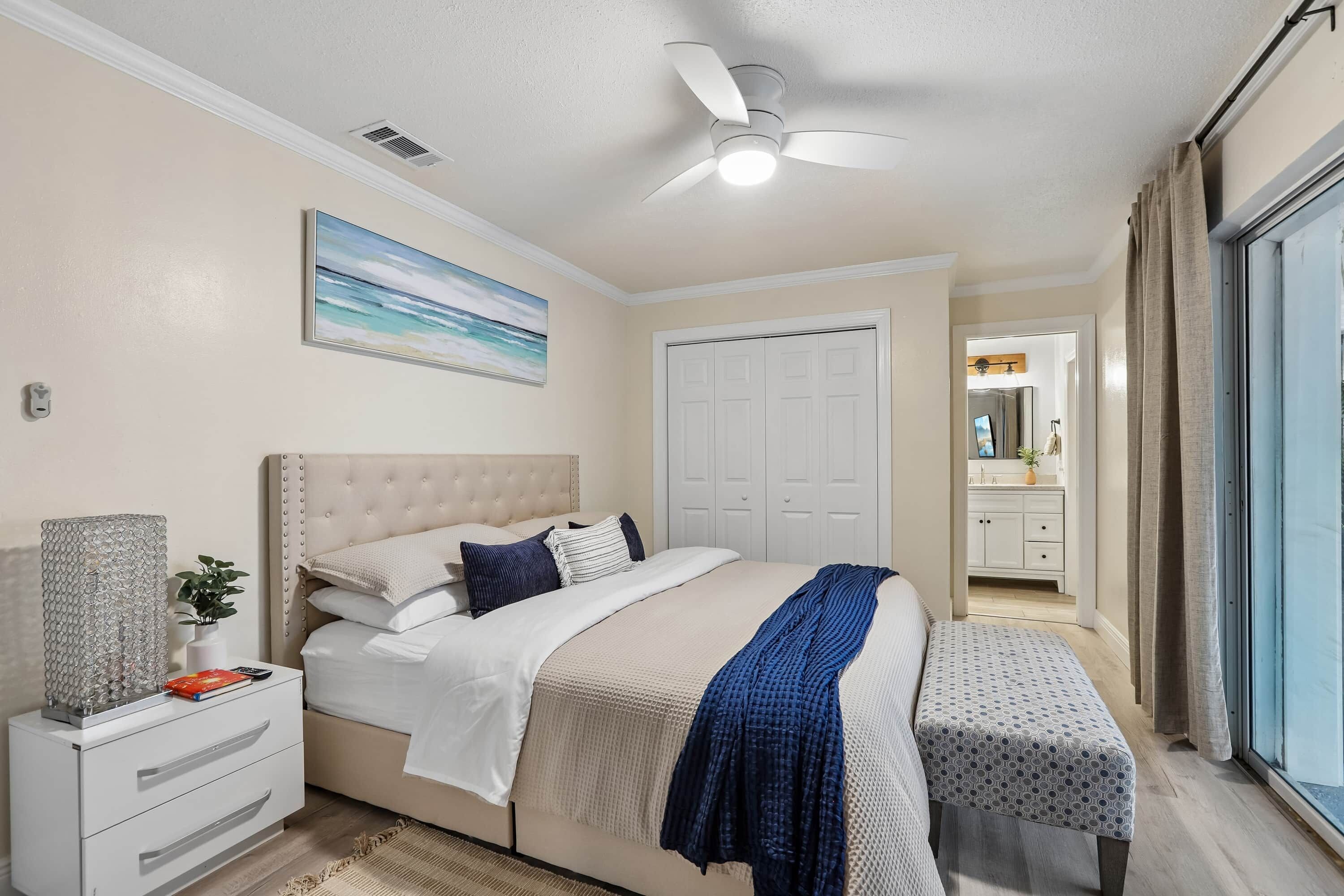 A bedroom with a bed, bedside table, and a ceiling fan.