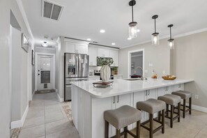 A modern kitchen with a central island, stainless steel appliances, and pendant lighting. - Pool, Mini Golf, Pool Table, Fire Pit, Sleeps 10 (Pinellas County)