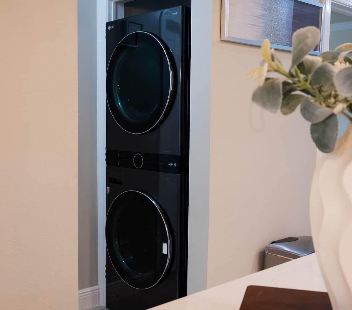 A laundry room with two front-loading washing machines and a trash can.