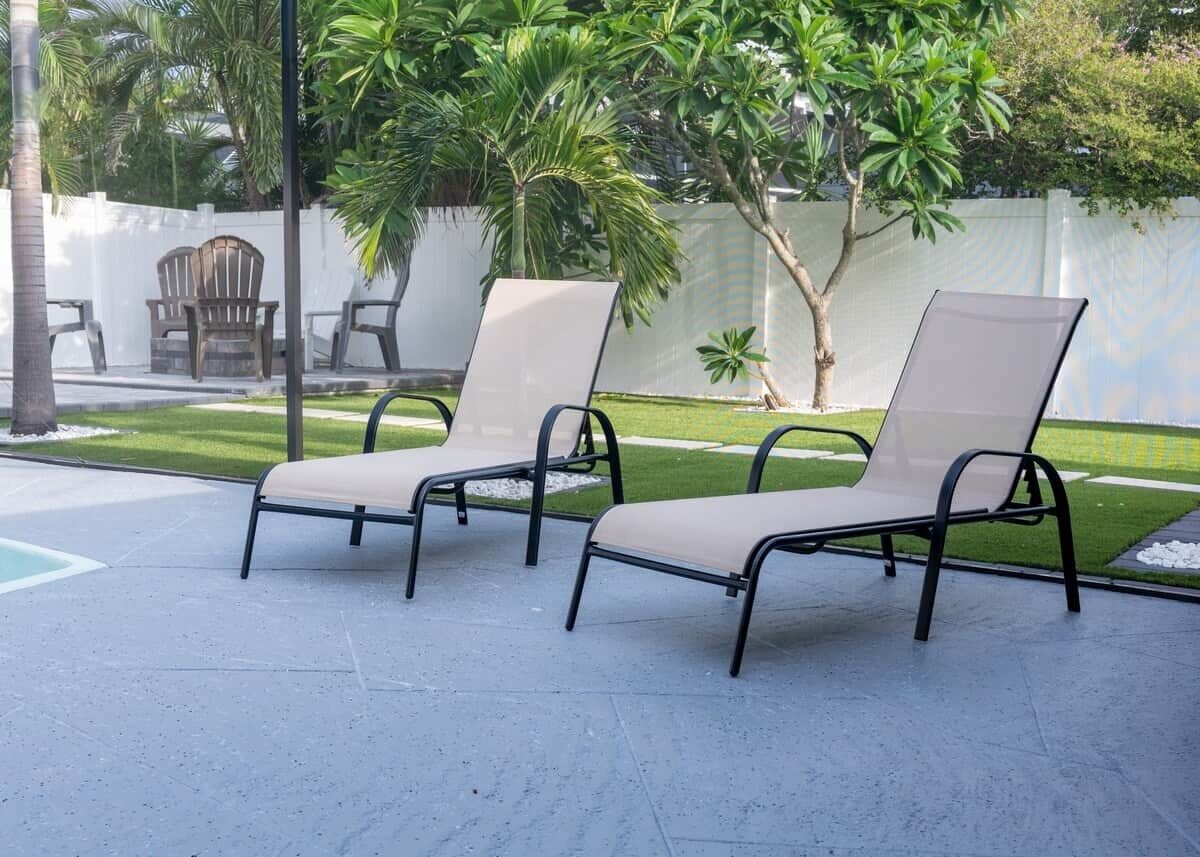 Zwei Liegestühle mit Metallgestell und beiger Polsterung, auf einer gepflasterten Terrasse platziert.