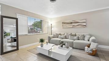 A modern living room with a sofa, coffee table, and a painting on the wall.