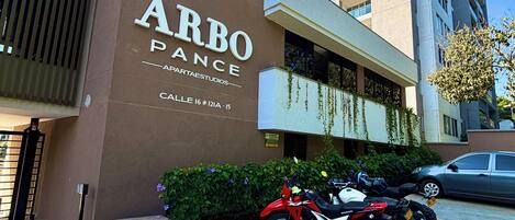 Un edificio con un cartel que dice 'ARBO PANCE' y un estacionamiento con motocicletas.