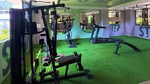 A gym with exercise equipment, a treadmill, and a green artificial turf floor. - ApartaEstudio Pance - Wifi y Coworking (Cali)