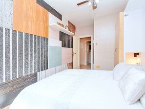 Ein Schlafzimmer mit einem Bett, einem Deckenventilator, einer Tür und einer Wand mit einer strukturierten Oberfläche.