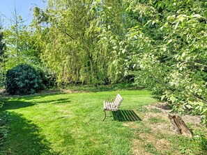 A grassy outdoor area with a metal bench and dense foliage. - Gîte La Grenouillère by Interhome (Esquéhéries)