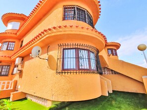 Ein Gebäude mit geschwungener Fassade, Satellitenschüssel und einem kleinen Balkon.