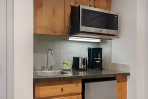 Eine Küche mit Mikrowelle, Toaster, Kaffeemaschine, Spüle und Holzschränken.
