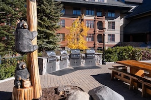 A patio area with a stone barbecue grill, a wooden bench, and a bear statue. - Marriott Timber Lodge - Premier Resort 2 Bedroom Villa condo at Heavenly gondola (South Lake Tahoe)