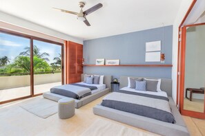 A modern bedroom with two beds, a ceiling fan, and a view of palm trees. - Condo Terramar 4BD - Terrazas Punta Mita (Punta de Mita)