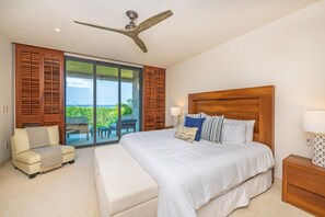 A bedroom with a large bed, a ceiling fan, a sofa, and a view of a balcony. - Condo Balboa 3BD - Tau Punta Mita (Punta de Mita)