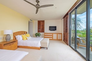 A bedroom with a bed, bedside table, lamp, TV, and a view of the outdoors. - Condo Balboa 3BD - Tau Punta Mita (Punta de Mita)