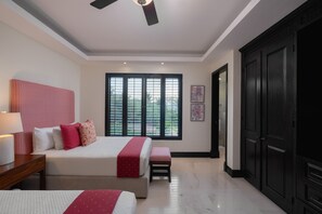 Ein Schlafzimmer mit einem Bett, Nachttischen, einem Fenster mit Jalousien, einem Deckenventilator und einem Kleiderschrank.