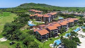 A resort with multiple buildings, a golf course, and a pool area. - Condo Azalea 4BD - Hacienda De Mita (Punta de Mita)