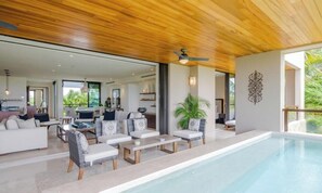 A modern interior with a pool, wooden ceiling, and a living area with sofas and a coffee table. - Condo Aries 3BD - Marietas Punta Mita (Punta de Mita)