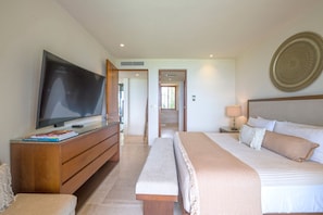 A hotel room with a large bed, a TV on a wooden cabinet, a bedside table with a lamp, and a decorative wall plate. - Condo Aries 3BD - Marietas Punta Mita (Punta de Mita)