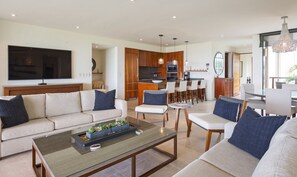 A modern living room with a sofa, coffee table, and a TV. - Condo Aries 3BD - Marietas Punta Mita (Punta de Mita)