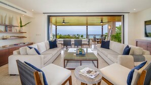 Una sala de estar moderna con un amplio sofá, una mesa de centro y vistas al océano.