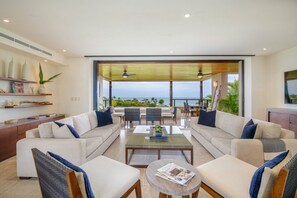 A modern living room with a large sofa set, a coffee table, and a view of the ocean. - Condo Aries 3BD - Marietas Punta Mita (Punta de Mita)