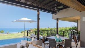 Ein Poolbereich mit Blick auf das Meer, ein Tisch mit Stühlen und ein Teleskop.