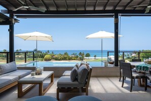 A covered outdoor seating area with a view of the ocean, a pool, and a golf course. - Condo Piscis 3BD - Marietas Punta Mita (Punta de Mita)