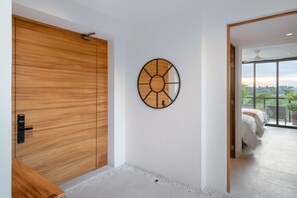 A modern interior with a wooden sliding door, a circular wall art piece, and a view of a balcony with a bed. - Condo Piscis 3BD - Marietas Punta Mita (Punta de Mita)