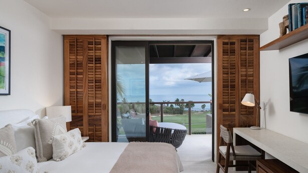 Ein Schlafzimmer mit Bett, Schreibtisch und Blick auf einen Golfplatz.