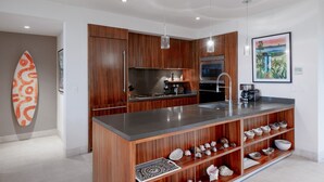 Eine moderne Küche mit Holzausstattung, Edelstahlgeräten und einer zentralen Kochinsel mit integriertem Spülbecken.