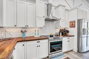 Una cucina moderna con mobili bianchi, piano cottura in acciaio inossidabile e forno integrato.