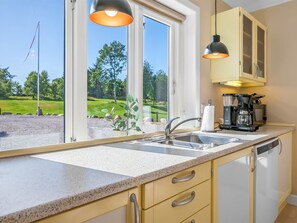 A kitchen with a sink, countertop, and cabinets, with a view of a green landscape through the window. - "Alkmar" - 6.5km from the sea by Interhome (Ørum Djurs)