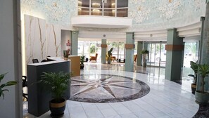 Un'ampia hall con reception, zona relax e un decorativo motivo pavimentale.