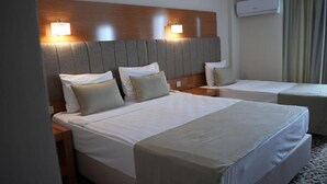 A hotel room with two beds, a wooden headboard, bedside lamps, an air conditioning unit, and a patterned carpet. - Ada Newday Resort Hotel & Spa (Kuşadası)