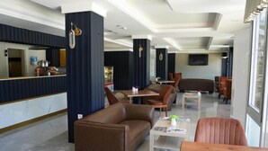 A modern hotel lobby with a bar area, seating arrangements, and a television. - Ada Newday Resort Hotel & Spa (Kuşadası)