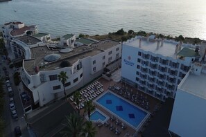 Un hotel con piscina sul tetto, vista sulla spiaggia e un cartello con la scritta 'NEWDAY'.