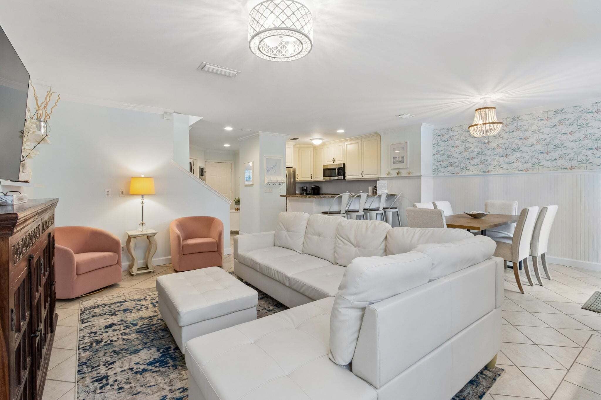 A modern living room with a sectional sofa, two armchairs, a coffee table, and a dining area with a table and chairs.